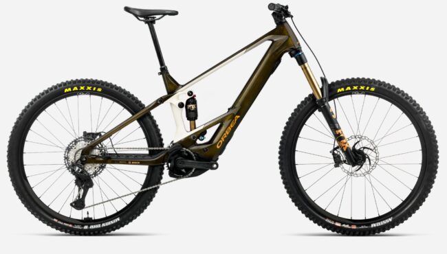 # Revisión Orbea Wild 2026 La **Orbea Wild 2026** es, sin ninguna duda, una de las bicicletas eléctricas de montaña más esperadas del año, fruto de una evolución constante y de una clara apuesta de la marca vasca por el alto rendimiento, la tecnología de vanguardia y la personalización extrema. En esta *revisión Orbea Wild 2026* te traigo un análisis exhaustivo sobre sus novedades, geometría, motores, versiones, configuraciones y sensaciones en el trail, profundizando en lo que realmente importa a quien busca una e-enduro radical, pero versátil y lista para cualquier desafío. --- ## Introducción: El renacimiento de una leyenda eléctrica Hablar de la **Orbea Wild** es hablar de un mito en el universo e-MTB. Tras ganar los principales comparativos y premios internacionales durante los últimos años, la Wild necesitaba responder a la llegada de nuevos motores, rivales cada vez mejor armados y la mayor exigencia de los bikers de enduro eléctricos. Orbea no ha decepcionado: la nueva Wild 2026 no solo actualiza, sino que reinventa gran parte de su propuesta integrando lo mejor de Bosch, refinando detalles clave y abriendo el abanico de opciones de personalización a cotas extraordinarias [(ESMTB)](https://esmtb.com/la-orbea-wild-2026-se-actualiza-mas-potencia-y-mas-opciones/). --- ## Novedades clave de la Orbea Wild 2026 El salto respecto al modelo anterior va mucho más allá de un simple restyling. A continuación, desglosamos las innovaciones más resaltables: ### Motor Bosch Performance Line CX: Más potencia, modos avanzados y versión Race La gama Wild 2026 estrena compatibilidad con la última generación de motores **Bosch Performance Line CX**. Ahora, en sus versiones estándar puede alcanzar un par máximo de **100 Nm** y una potencia pico de **750 W**, todo configurable desde la aplicación Flow y ofreciendo niveles de asistencia de hasta el 400%. Para los más competitivos, llega el **Bosch Performance Line CX Race**, más ligero y pensado específicamente para el máximo rendimiento en enduro y E-EDR, montado de serie en las versiones tope de gama como la M-LTD y disponible como opción en otras. ### Nuevo display Bosch System Module Kiox 400C Las versiones **M10**, **M-Team** y **M-LTD** reciben el nuevo display Bosch Kiox 400C, integrado en el cuadro, mucho más informativo, intuitivo y personalizable. Visualiza datos en tiempo real con mayor claridad y puede instalarse en modelos anteriores con sistema Bosch [(ESMTB)](https://esmtb.com/la-orbea-wild-2026-se-actualiza-mas-potencia-y-mas-opciones/). ### Cambios de marcha Free Shift: tecnología Shimano XTR y XT Estreno de la función **Free Shift** en los montajes con Shimano XTR y XT, que permite cambiar de marcha sin pedalear. Ideal para anticipar desarrollos en pleno descenso o para resolver pasos técnicos donde no se puede aplicar potencia al pedal. ### Versiones en carbono y aluminio, y opción "mullet" El catálogo Wild 2026 arranca en las exclusivas versiones OMR Carbono (M-LTD, M-Team) con ruedas de 29", y expande las opciones con **versiones mullet** (29" delante, 27,5" detrás) configurables en todos los montajes. Las nuevas **Wild Hydro** de aluminio democratizan la Wild e-MTB desde 5.299€, y mantienen la radicalidad en geometría y motores sin sacrificar calidad ni tecnología. ### Geometría progresiva y más personalización MyO La Wild sigue apostando por una geometría agresiva, pero equilibrada: dirección a **63,5º**, tubo de sillín de **77,5º**, y longitudes de tubo corto para permitir el uso de dropper posts extralargos (hasta 240 mm). Todo ello sumado al potente configurador **MyO** de Orbea, que permite personalizar colores, suspensiones, ruedas, grupo, tijas, cubiertas e infinidad de componentes. --- ## Análisis de la gama: M-LTD, M-Team y Wild Hydro ### Wild M-LTD (carbono OMR, CX Race, 29" o mullet) - Motor: Bosch CX Race 100 Nm/750W, serie - Batería: Bosch 750 Wh o 600 Wh + extender - Display: Kiox 400C - Ruedas: OQUO Carbono - Suspensión: FOX 38 Factory 170 mm, Float X2 Factory - Transmisión: Shimano XTR/XX Eagle AXS - Tija telescópica hasta 240 mm - Precio: **12.499 €** - Peso: desde **22,5 kg** (L) ### Wild M-Team y M10 (carbono OMR, CX o CX Race, 29" o mullet) - Motor: Bosch CX Gen 5, opción CX Race - Batería: 625/750 Wh - Display: Kiox 400C u opciones - Suspensión: FOX 38 Factory/Performance - Transmisión: Shimano XT o superiores - Precio: desde **9.999 €/7.999 €** ### Wild Hydro H10, H30 (aluminio, CX o CX Race, 29" o mullet) - Motor: Bosch CX Gen 5 o CX Race opcional - Ruedas: 29” o mullet (todas las versiones) - Suspensión: 170 mm - Tija de hasta 200 mm - Precio: H10 desde **6.999 €**, H30 desde **5.299 €** #### Todas las versiones pueden personalizarse con el configurador MyO respetando precio y montaje base. --- ## Geometría de la Orbea Wild 2026 Una de las señas de identidad de la Wild es su geometría, tan progresiva como apta para todos los públicos del e-enduro: | Talla | Reach | Stack | Chainstay | Tubo sillín | Dirección | Sillín | Wheelbase | |-------|-------|-------|-----------|-------------|-----------|--------|-----------| | S | 435 | 625 | 448 | 415 | 63,5º | 77,5º | 1228 | | M | 455 | 634 | 448 | 415 | 63,5º | 77,5º | 1252 | | L | 480 | 643 | 448 | 435 | 63,5º | 77,5º | 1282 | | XL | 505 | 652 | 448 | 450 | 63,5º | 77,5º | 1311 | Cabe destacar el dropper que desaparece totalmente incluso en talla pequeña, la opción de mullet sin alterar geometría, y la posibilidad de ajuste personalizado en MyO. --- ## Comportamiento en el sendero: respuesta y sensaciones reales La **revisión Orbea Wild 2026** no estaría completa sin hablar de las sensaciones reales sobre el terreno, y aquí la Wild se luce en varios apartados clave: ### Subidas técnicas: Motor Bosch y tracción total El nuevo **Bosch Performance Line CX** (y más aún la versión Race) marca un antes y un después: no solo por su fuerza brutal al arrancar sino por su control de la entrega (gracias a sensores mejorados) y la asistencia dinámica configurable por app. En subidas imposibles, las ruedas 29” y la posición centrada logran un grip espectacular, asistido por el excelente reparto de peso y el anti-squat afinado de la suspensión. ### Bajadas: estabilidad radical, feeling de enduro puro Con 170 mm de recorrido, dirección slack y un chasis rígido pero bien amortiguado, la Wild permite atacar cortados, raíces y rocas a la velocidad que te atrevas. El nuevo setting de FOX, especialmente con la X2, da margen a setup personalizado según peso y uso. La absorción es de primer nivel, y el control aún mayor en las versiones con cubiertas Maxxis DH Casing MaxxGrip. El bajo centro de gravedad, el peso contenido para tener batería de gran tamaño y motor potente (en torno a 22-23 kg M-LTD), hacen que la Wild se sienta viva bajando, sin perder soltura respecto a e-bikes más ligeras, aunque quizás no alcance la agilidad de una trail específica o de su hermana Rise. ### Terrenos mixtos y largos recorridos La opción de range extender y el buen soporte en modos Eco, Tour+ o EMTB+ permiten rutas muy largas para el segmento, logrando autonomías de hasta 80 km y +2200 m con el combo 600 + 250 Wh. El nuevo display y la conexión con Strava, Komoot, etc., aportan información útil y clara sobre estado del motor, modos y autonomía restante. --- ## Equipamiento y detalles diferenciales - **Display Kiox 400C**: personalizable, color, legible al sol, admite actualizaciones por app y conexión a sensores externos. - **Tija telescópica 240 mm**: en carbono M-LTD, se esconde completamente incluso en tallas medianas, máxima libertad. - **Ruedas OQUO carbono**: ligeras, resistentes y montadas en fábrica sin sobrepeso. - **Transmisiones AXS y Shimano XTR con Free Shift**: cambios impecables incluso sin pedalear. - **Suspensiones FOX Factory Factory/X2 y GRIP X2**: configuración multiregulación top. - **Sellado de cableado SIC**: cables internos por la dirección, estéticamente limpio pero complicado para mecánica doméstica. - **Protecciones generosas (TPU en vaina y tubo diagonal)** y detalles pensados para ruta y competición. --- ## Peso, autonomía y comparativas ### Pesos reales (según montaje y talla) - M-LTD (carbono, CX Race, 600Wh): **22,3-22,5 kg** - M-Team/M10 (carbono/aluminio, CX, 750Wh): **23,5-24 kg** - Wild Hydro H10 (aluminio, CX): **24-25,2 kg** El peso es notablemente bajo teniendo en cuenta la batería interna y las ruedas DH; además, la diferencia entre 600 Wh y 750 Wh es de casi 1,5 kg. ### Autonomía - 600 Wh + Range extender 250 Wh: hasta **90 km** y 2700 m+, según terreno y modo usado - 750 Wh sola: hasta **110 km** en modos Eco/Tour ### Comparativas y premios La Orbea Wild ha ganado los comparativos de **e-MTB 2023-2025** en medios como E-Mountainbike Magazine, The Loam Wolf y Enduro MTB. En 2026 se espera que repita liderazgo gracias a las mejoras tecnológicas y la llegada del CX Race 100 Nm [(Enduro MTB)](https://enduro-mtb.com/en/best-enduro-bike-orbea-wild-m-ltd/) [(The Loam Wolf)](https://theloamwolf.com/emtb/orbea-wild-m-team-review-2025-emtb-shootout/). --- ## Valoración y opiniones: Pros y contras ### Puntos fuertes - Motor Bosch CX Race y 100 Nm: potencia líder y fiabilidad total. - Geometría y suspensión de enduro pura (170 mm): absorción, confianza y segurida. - Customización real: colores, montaje, transmisiones, tija, ruedas, cubiertas (MyO a coste 0/ajustado). - Peso muy bajo para la categoría (~22 kg competitivo con eMTB ligeras). - Electrónica de última generación (Kiox 400C, Free Shift, app Flow). - Integración, estética y ausencia de ruidos. - Estructura del cuadro: sellado, soporte y protección. - Dropper posts ultralargos totalmente rentables para todas las tallas. ### Puntos a mejorar - Extracción de batería interna complicada (hay que desmontar motor, opción solo útil para mantenimientos). - Cableado por dirección: muy bonito, poco amigable para mecánica casera. - Precio elevado en versiones M-LTD: desde 12.499 €, aunque justificado por componentes y personalización. - Algunos usuarios pueden echar de menos la agilidad de e-bikes más ligeras; no es la más juguetona del segmento. - Las cubiertas de compuesto blando MaxxGrip dan mucho grip pero se desgastan rápido con uso intensivo. --- ## ¿Para quién es la Orbea Wild 2026? La **Orbea Wild 2026** es la elección indiscutible si buscas: - Máximo rendimiento eléctrico en enduro, con potencia/configuración de carreras. - Bicicleta robusta y estable en bajadas extremas pero todavía eficaz en rutas largas/mixtas. - Capacidad de personalizar la bici al milímetro, tanto en colores como en componentes. - Un motor potente, actualizable y conectado. - Chasis rígido, moderno y fiable para uso intensivo, maratón enduro o incluso bikepark. No es la opción ideal si priorizas manejo ultraágil o la ligereza extrema por encima del rendimiento full-power, en cuyo caso una Orbea Rise o una e-MTB trail ligera puede ajustarse mejor. --- ## Preguntas frecuentes sobre la Orbea Wild 2026 ### ¿Qué diferencia hay entre el motor Bosch CX y el CX Race? El Bosch CX Race ofrece el mismo par máximo (100 Nm) que el actualizado CX Gen 5, pero es más ligero, tiene una entrega más agresiva y modos adicionales pensados para competición y sprint en tramos técnicos. Ideal si buscas máximo rendimiento en carreras de enduro o E-EDR. El CX estándar es más equilibrado para uso mixto ocio/competición.[(ESMTB)](https://esmtb.com/la-orbea-wild-2026-se-actualiza-mas-potencia-y-mas-opciones/) ### ¿Se puede elegir la configuración mullet en fábrica? Sí. Tanto la gama en carbono como la de aluminio pueden configurarse como **mullet** (29" delante, 27,5" detrás) desde el pedido. Es posible elegir/ajustar montajes y geometría específica sin coste añadido. ### ¿La batería se puede cambiar fácilmente? No. La batería está muy integrada para dar rigidez al cuadro; solo mecánicos experimentados (o servicios técnicos) pueden extraerla, ya que requiere desmontaje parcial del motor. En uso real, el cambio de batería en ruta no es viable. ### ¿Existe app para configuración y actualizaciones? Sí. La **Bosch Flow app** permite actualizar firmware, personalizar modos de motor, visualizar parámetros y conectarse con otras apps como Strava o diagnosticar problemas eléctricos. ### ¿El display Kiox 400C es retrocompatible? Sí, se puede instalar en Orbea Wild anteriores equipadas con sistema Bosch Smart System (a partir de 2023). ### ¿Qué autonomía real ofrece la Wild 2026? Depende del peso, modo, batería y terreno, pero en términos medios: - 600 Wh: hasta 60-80 km uso real mixto - 750 Wh: hasta 90-110 km - 600+250 Wh extender: hasta 100km y >2200m+, ideal para rutas alpinas o maratones. ### ¿Cuál es la garantía del cuadro? **Garantía de por vida** para defectos de fabricación en cuadros Wild en todas las versiones, registrada en Orbea y acompañada del número de serie correspondiente. ### ¿Cuánto pesa la Wild 2026 realmente? Según versión y talla, alrededor de **22,3 kg en carbono M-LTD con batería 600 Wh**, y hasta 24-25 kg en versión hidroformada (aluminio) con baterías de gran capacidad y cubiertas DH. ### ¿Es recomendable para bikepark o solo para enduro natural? Totalmente compatible con uso de bikepark, gracias al recorrido, rigidez, ruedas reforzadas y suspensiones premium. Suffre menos en largas sesiones intensivas que e-bikes ligeras o rígidas. --- ## Conclusión de la revisión Orbea Wild 2026 La **revisión Orbea Wild 2026** confirma por qué esta e-MTB es referente global. Orbea ha logrado elevar su plataforma a un nivel casi obsesivo de detalle: motores a la última, geometría optimizada, componentes tope de gama y una personalización que la convierte en una herramienta única para cada rider. Si tu prioridad es el rendimiento absoluto en enduro eléctrico, con garantía de éxito y fiabilidad, la Wild 2026 debería estar en lo más alto de tu lista. Da igual si mides 1,60 o 1,95, si prefieres el peso pluma o no te importa cargar con ruedas DH para ir más rápido por los senderos más exigentes: la Orbea Wild te permite encontrar tu configuración perfecta. La innovación en integración (display, motores, Free Shift, cableado) y la posibilidad de ajustes de motor y componentes la sitúan a la cabeza en rendimiento y experiencia de usuario. Orbea no solo reafirma su dominio en el segmento; establece el estándar para las e-MTB de enduro de nueva generación. --- **Fuentes/Citas:** - Análisis y datos técnicos, geometría, motores y componentes: ESMTB [(ESMTB)](https://esmtb.com/la-orbea-wild-2026-se-actualiza-mas-potencia-y-mas-opciones/) - Tests de comportamiento y sensaciones: Enduro MTB Magazine [(Enduro MTB)](https://enduro-mtb.com/en/best-enduro-bike-orbea-wild-m-ltd/), The Loam Wolf [(The Loam Wolf)](https://theloamwolf.com/emtb/orbea-wild-m-team-review-2025-emtb-shootout/) - Especificaciones, autonomía real, precios y opciones: Pinkbike, ebike-mtb.com, Orbea oficial --- Para más dudas o comparativas, deja tu comentario y comparte tu experiencia con la nueva **Orbea Wild 2026**. ¿Listo para electrificar tus trails?