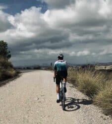 Bicicleta de perfil en ruta exterior con paisaje de cinturón montañoso y cielo nublado.
