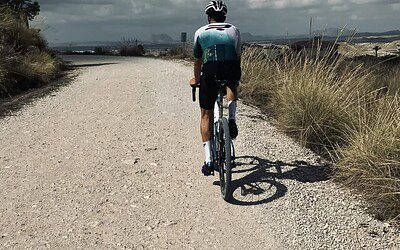 Bicicleta de perfil en ruta exterior con paisaje de cinturón montañoso y cielo nublado.
