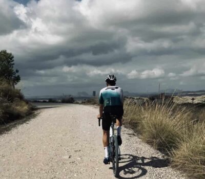 Bicicleta de perfil en ruta exterior con paisaje de cinturón montañoso y cielo nublado.