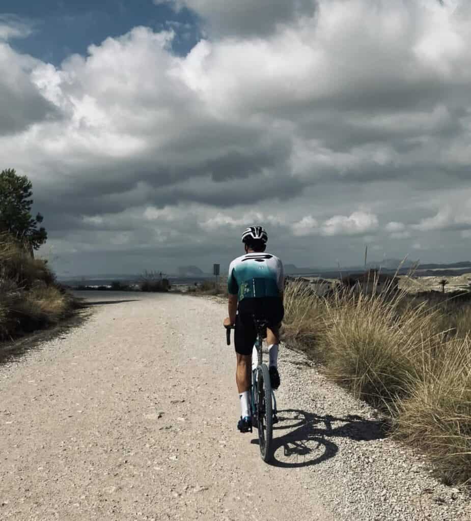 Bicicleta de perfil en ruta exterior con paisaje de cinturón montañoso y cielo nublado.