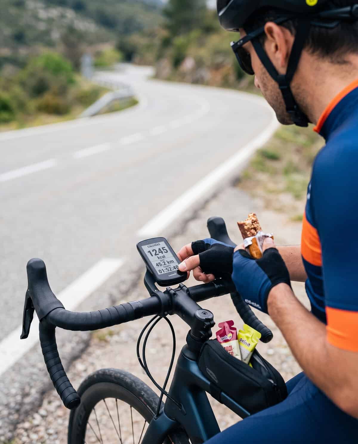 Ciclista consultando datos de calorías quemadas en el ciclocomputador durante una salida